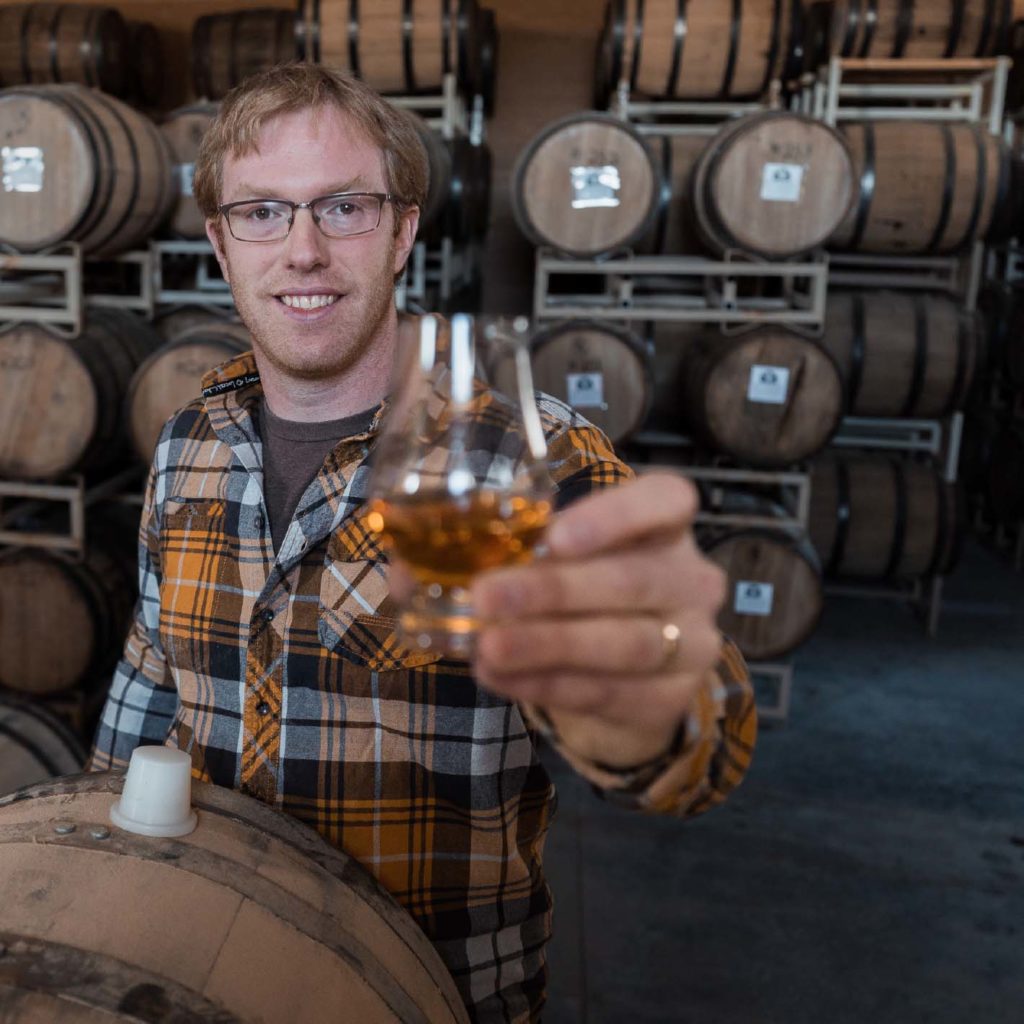 head distiller garret haynes holding up a glass of Meeting Creek Whisky
